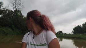 en canoa tradicional, de madera, navegando el río Dungre, en Sauraha, un río de aguas color marrón y vegetación tropical a los lados, en cada orilla.