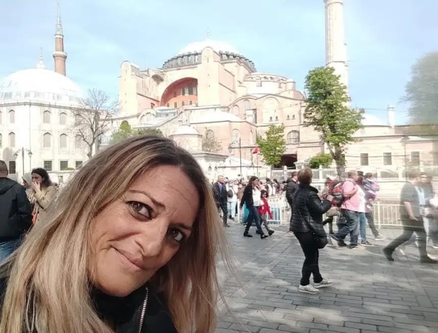 Mujer en primer plano, en una plaza y al fondo, la vista de la mezquita de Sultán Ahmed o mezquita azul